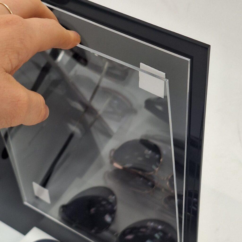Close-up of the interchangeable graphic panel on the WAX eyewear countertop display, showing the removable clear acrylic graphic holder designed for quick seasonal artwork changes.