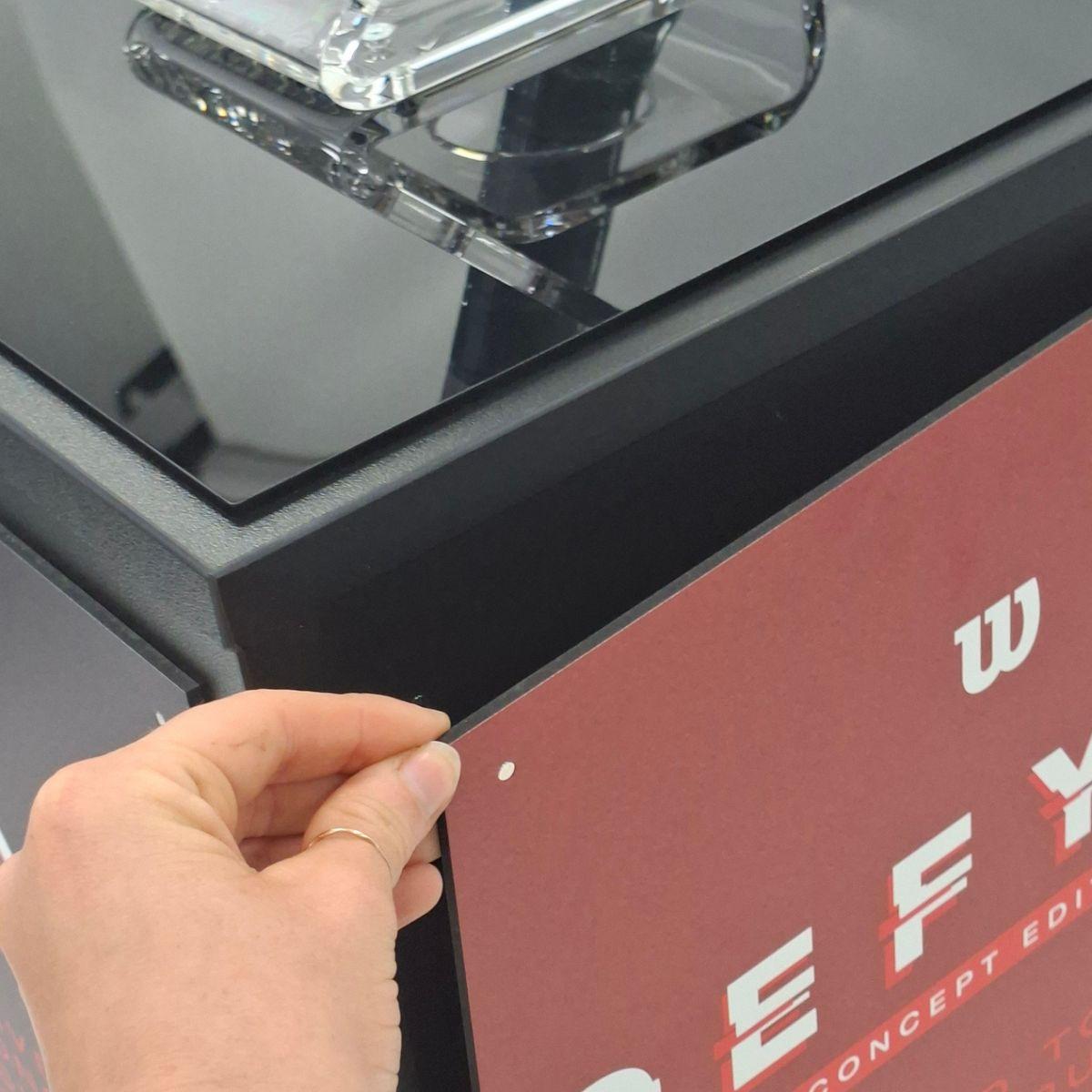 Close-up of interchangeable magnetic graphic panel being fitted to a branded retail display plinth